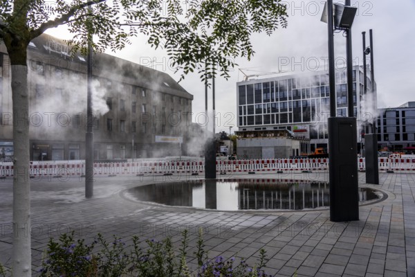 Digital water feature, Blue Cloud water installation on Husemanplatz in downtown Bochum, water mist is sprayed from 4 metal masts, which, in conjunction with the circular water surface, is intended to cool the surrounding area when it is hot, colored light images are projected into the water mist via projectors, part of the transformation of Husemanplatz