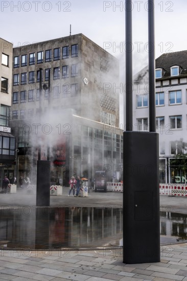 Digital water feature, Blue Cloud water installation on Husemanplatz in downtown Bochum, water mist is sprayed from 4 metal masts, which, in conjunction with the circular water surface, is intended to cool the surrounding area when it is hot, colored light images are projected into the water mist via projectors, part of the transformation of Husemanplatz