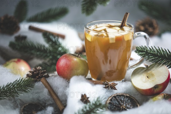 A glass of apple punch and apple pieces in a wintery setting