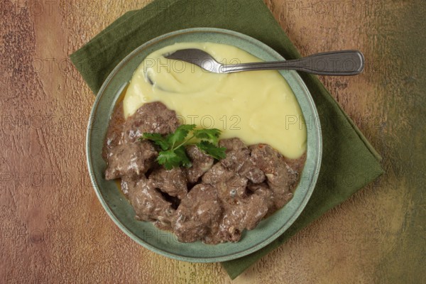 Liver beef stroganoff with mashed potatoes, table setting in green tones, homemade