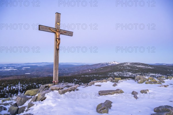 Christian cross on the peak of Mount Lusen with the view over the hills of the bavarian forest at sunrise at winter, Bavaria, Germany