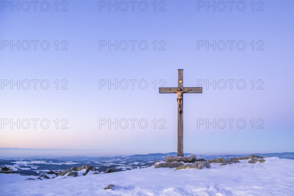 Christian cross on the peak of Mount Lusen with the view over the hills of the bavarian forest at sunrise at winter, Bavaria, Germany