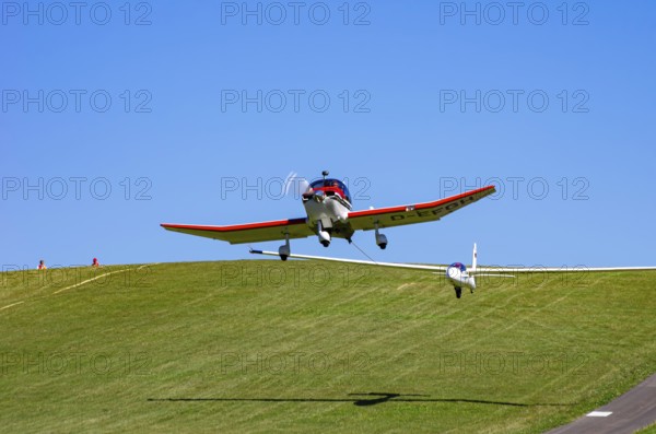 A Robin DR 400/200R Remorqueur light aircraft, registration D-EFGH, tows a glider during a flight demonstration as part of an air show on Rossfeld in Metzingen-Glems, Baden-Württemberg, Germany, for editorial use only