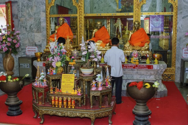 Buddhist believers Buddhists pray making offerings to statues of Buddhist monks covered with gold leaf at Wat Chalong Monastery, Wat Chaithararam, Phuket Island, Phuket Province, Thailand
