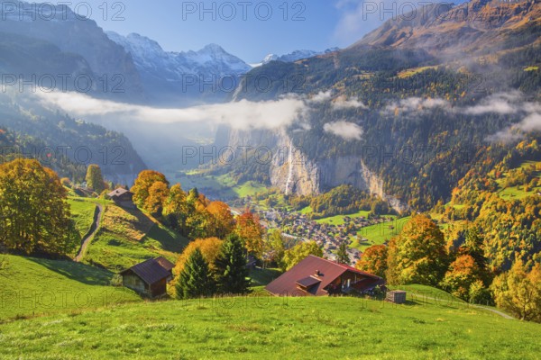 View from the village of the Lauterbrunnen Valley with Staubbach waterfall in autumn with morning fog, Wengen, Bernese Oberland, Canton of Bern, Switzerland