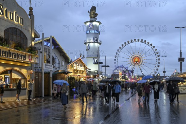 Oktoberfest visitors with umbrellas, rainy meadows, Löwenbräuturm, Ferris wheel, Munich, Bavaria, Germany