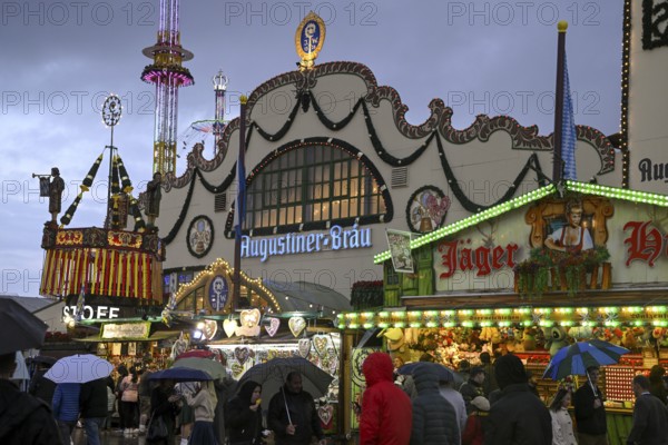 Oktoberfest visitors with umbrellas, rainy meadows, Augustiner festival tent, Munich, Bavaria, Germany