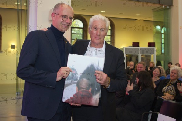 Richard Gere (International Chairman of the International Campaign for Tibet) receives a personal gift from Michael Brand (MdB) (photo of the Dalai Llama at the Brandenburg Gate in 1989), at the presentation of the Snow Lion Human Rights Prize, Umweltforum Berlin, 25.10.2025