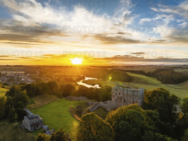 Sunset over Norham Castle and River Tweed from a drone, Norham, Northumberland, England, United Kingdom