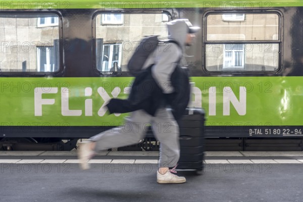 Flixtrain train on track 2 in Essen main station, passenger runs with luggage to reach his train, North Rhine-Westphalia, Germany
