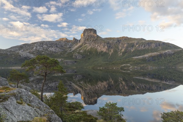 Morning dream over the quiet Steigtindvatnet near Bodø. Pine forest on the rock face at sunrise