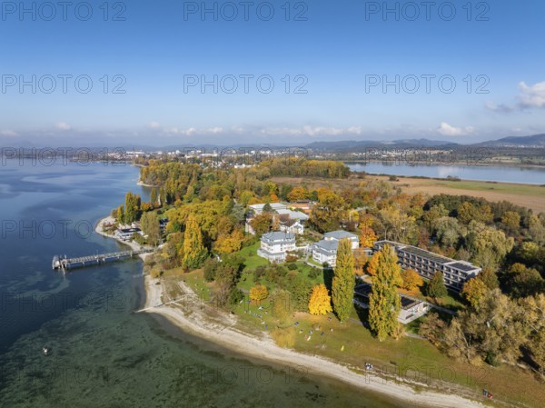 Aerial view of the Mettnau peninsula, surrounded by autumn vegetation, in western Lake Constance with the spa center, Mettnaukur, boat dock and restaurant Strandcafe, Radolfzell, Konstanz district, Baden-Württemberg, Germany