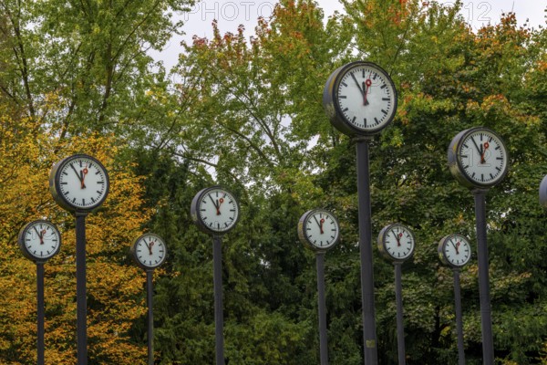 The art installation Zeitfeld in Volksgarten Park in Düsseldorf-Oberbilk, a total of 24 station clocks, on 6 meter high steel columns, have been running synchronously since 1987, dial shows five to twelve, artwork by Düsseldorf artist Klaus Rinke, symbol of time, time change, North Rhine-Westphalia, Germany
