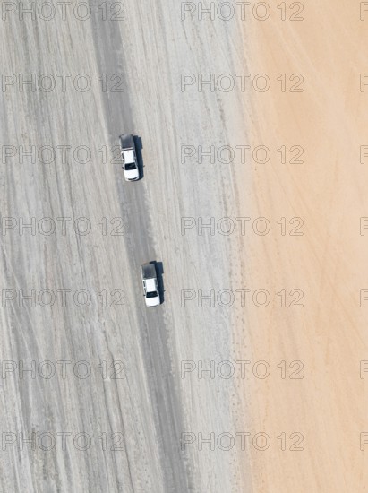 Aerial view, top-down view, two off-road cars driving on a road in arid countryside, Botswana