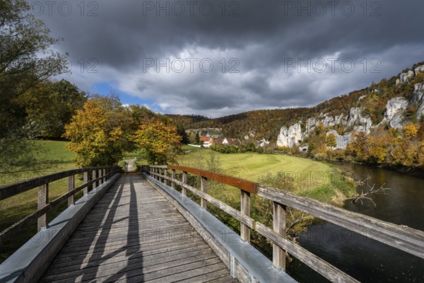 Wooden bridge across the Danube to Käppeler Manor with St. George's Basilica near Thiergarten in the Upper Danube Valley, surrounded by autumn vegetation, Sigmaringen district, Baden-Württemberg, Germany