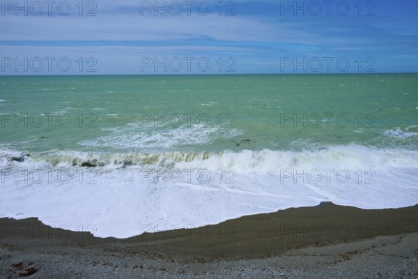 Green sea with waves, clear sky and pebble beach, Tuhawaiki Point Lighthouse or Jack's Point Lighthouse, Scarborough, Timaru, South Island, New Zealand