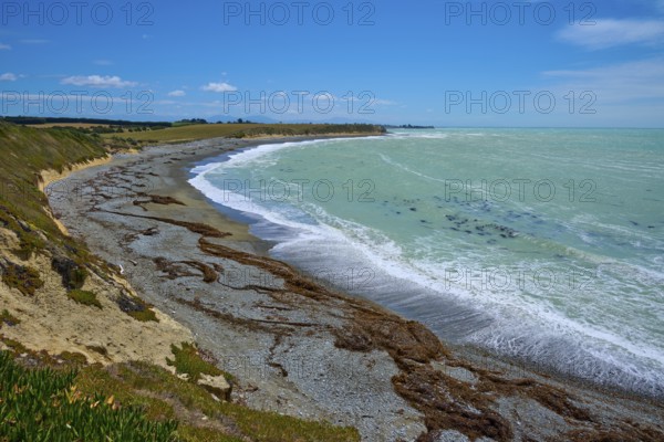 Long stretch of coastline with wavy sea and blue sky, Tuhawaiki Point Lighthouse or Jack's Point Lighthouse, Scarborough, Timaru, South Island, New Zealand