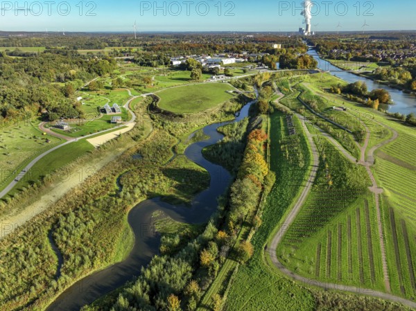Castrop-Rauxel, North Rhine-Westphalia, Germany - Autumn on the restored Emscher, EMSCHERLAND adventure park, a new nature and water adventure park on the restored Emscher, at the Emscher water cross with the Rhine-Herne Canal on the city limits of Recklinghausen and Castrop-Rauxel. A new vineyard in front. Flood protection through area expansion. The ecological focus at the confluence of the Suderwicher Bach and Emscher rivers will also be a future garden of the IGA 2027 International Garden Exhibition. Before the restoration, the river system of the Emscher was an open, aboveground waste water channel, mixed water channel with surface water and waste water. Back right, the new bridge jump over the Emscher. On the horizon the Datteln 4 power plant
