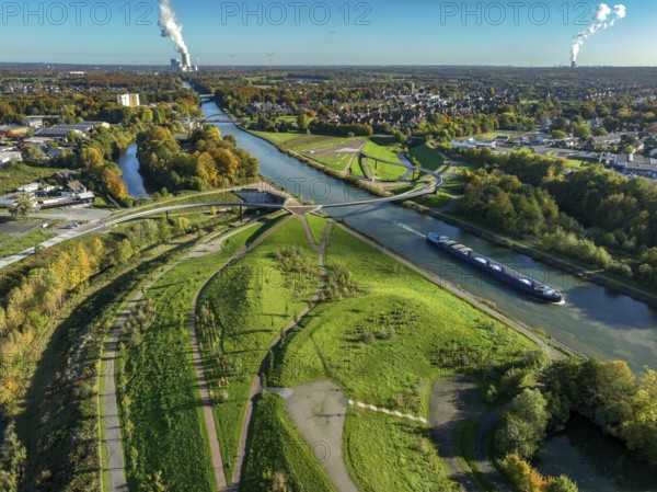 Castrop-Rauxel, North Rhine-Westphalia, Germany - Autumn on the restored Emscher, EMSCHERLAND adventure park, a new nature and water adventure park on the restored Emscher, at the Emscher water cross with the Rhine-Herne Canal on the city limits of Recklinghausen and Castrop-Rauxel. Flood protection through area expansion. The ecological focus at the confluence of the Suderwicher Bach and Emscher rivers will also be a future garden of the IGA 2027 International Garden Exhibition. Before the restoration, the river system of the Emscher was an open, aboveground waste water channel, mixed water channel with surface water and waste water. Back right, the new bridge jump over the Emscher. On the horizon the Datteln 4 power plant