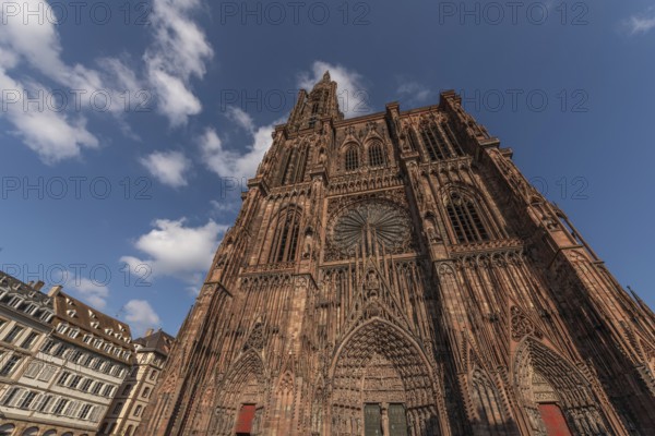 Strasbourg's Notre Dame Cathedral stands majestically there. Its magnificent architectural details are clearly visible under the blue, cloudy sky. Bas Rhin, Alsace, France