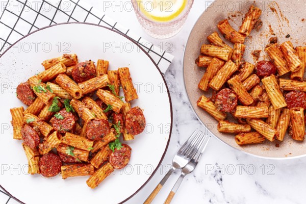 Rigatoni pasta with spicy sausage, and rich tomato sauce served, on a white plate, homemade