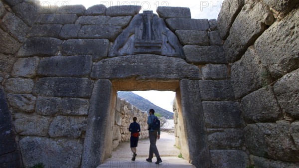 Couple walking through a huge stone gate, lion gate, Mycenae, archaeological site, UNESCO World Heritage Site, Mycenae, Mycenae, important city in pre-classical times, Peloponnese, peninsula, Greece