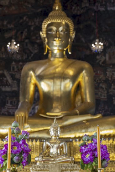 Golden Buddha statue, Phra Buddha Trilokachet surrounded by exquisite wall paintings, interior view of Phra Ubosot or ordination hall, Wat Suthat Thepwararam, Royal Temple, Phra Nakhon, Bangkok, Thailand