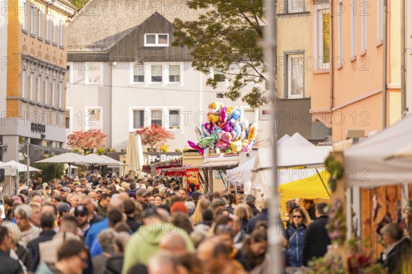 Busy shopping street in autumn, people strolling between modern buildings and colorful shops, Urschelherbst street festival, Nagold, Germany