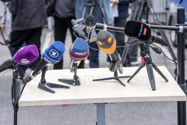 Microphones from various radio stations, television stations, standing on the table, at a press conference