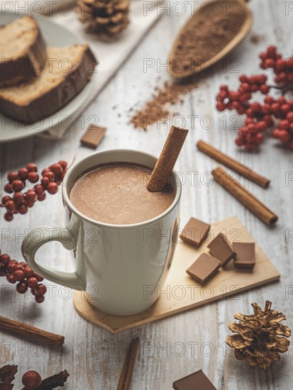 Cup of hot chocolate with cinnamon stick, autumn decorations, cake and berries