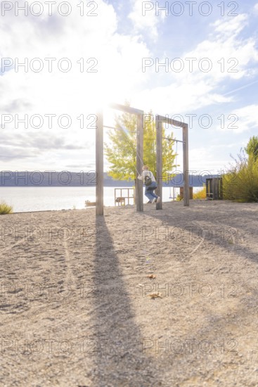 Lakeside swing with sun and long shade on the sand, Überlingen, Lake Constance, Germany