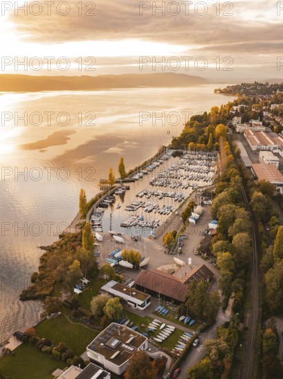A harbor with anchored boats at sunset, surrounded by an urban landscape in autumn, Überlingen, Lake Constance, Germany