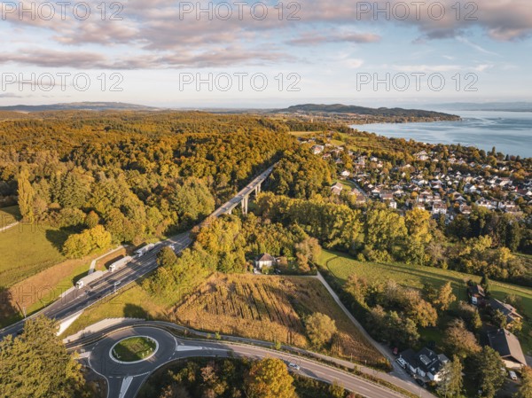 Highway through a forest, with a view of a nearby town and the lake on the horizon under clouds, Überlingen, Lake Constance, Germany