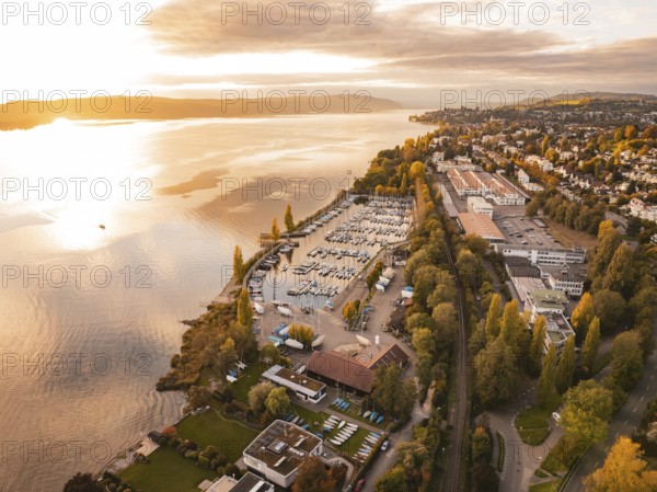 Harbour with boats on an autumn evening at sunset, surrounded by an urban landscape, Überlingen, Lake Constance, Germany