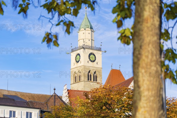 Church tower against blue sky with autumn leaves in the foreground, Überlingen, Lake Constance, Germany
