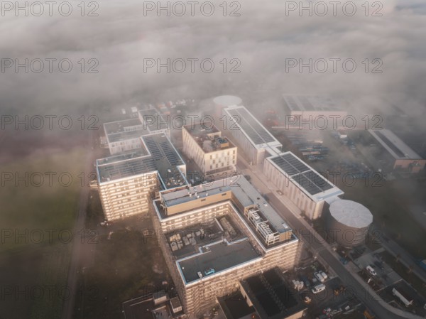 Aerial view of an industrial complex in morning fog with thick cloud cover, new hospital health campus building, Calw, Germany