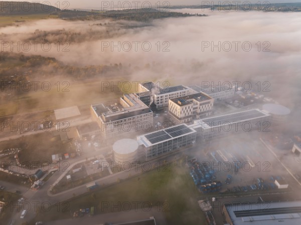 Bird's-eye view of industrial building group in mystical fog weather, new hospital health campus building, Calw, Germany