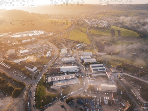 Sunrise over a village with adjacent fields and winding roads, new hospital health campus building, Calw, Germany