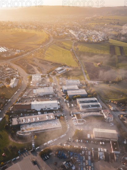 Aerial view of a village in morning light surrounded by rolling fields, new hospital health campus building, Calw, Germany