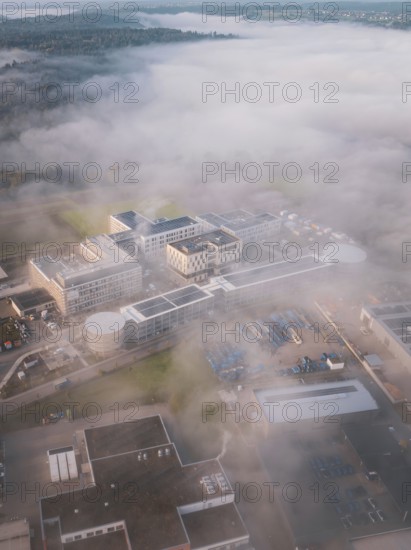 Wide landscape with industrial complex in fog from an aerial perspective, new hospital health campus building, Calw, Germany