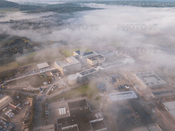Wide angle view of an industrial center in fog surrounded by natural landscape at dawn, new hospital health campus building, Calw, Germany