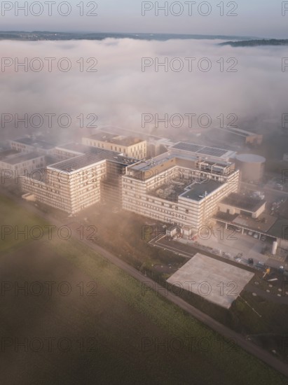 Building complex in dreamy fog, taken from the air early in the morning with blurred colors, new hospital health campus building, Calw, Germany