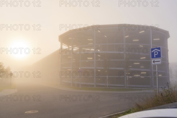 Misty street with parking garage at sunrise, mystical atmosphere, new hospital health campus building, Calw, Germany