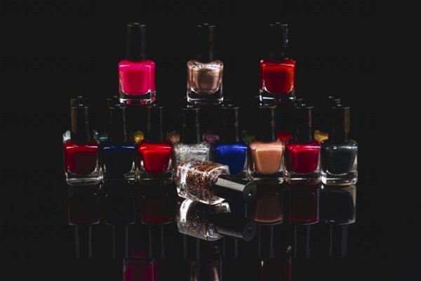 Colourful nail polish bottles with reflections against a black background