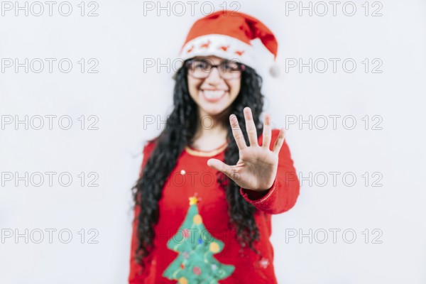 Smiling girl in Christmas sweater counting five. Funny girl in a Christmas hat counting five, isolated