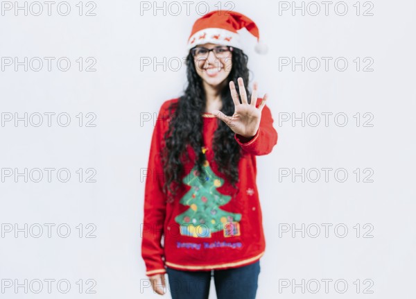 Funny girl in Christmas hat counting five, isolated. Smiling girl in Christmas sweater counting five
