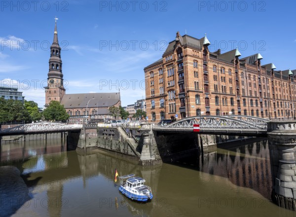 Boat on the Kleines Fleet canal with Kannengießer bridge and tower of the main church of St. Katharinen, Speicherstadt. Hamburg, Germany