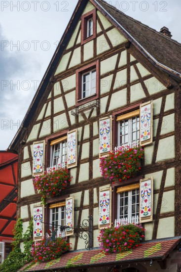 Decorated half-timbered house with ornate windows and flowers in the old town centre of Kaysersberg
