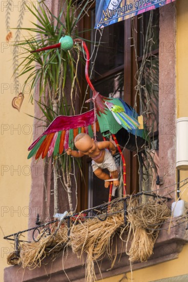 Decorated house wall with stork and baby in the old town centre of Ribeauvillè