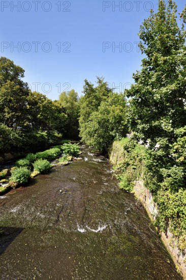 Ettlingen, Germany - August 13th 2025: Alb river flowing through Ettlingen in summer with trees and blue sky